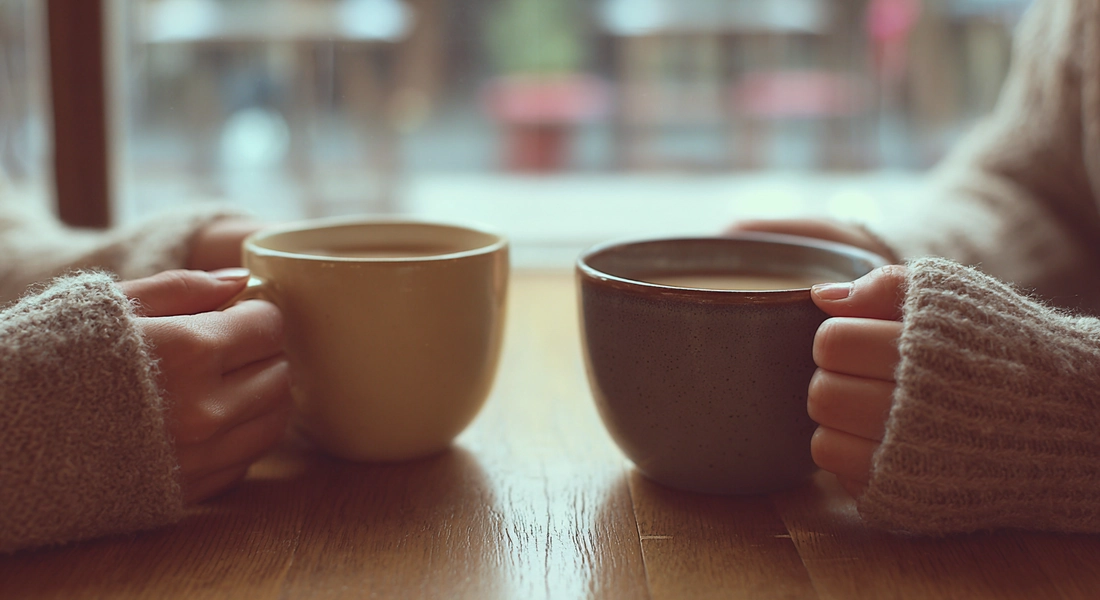 Hände halten respektvoll eine Tasse Kaffee in ruhiger Umgebung